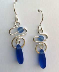 the earrings are made with wire and blue sea glass, as well as silver earwires