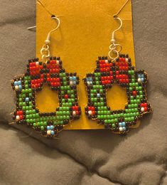 a pair of colorful beaded earrings sitting on top of a yellow card