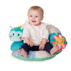 a baby sitting on top of a pillow with stuffed animals around it's legs