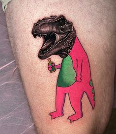 a man's leg with a dinosaur tattoo on it, holding a drink in his hand