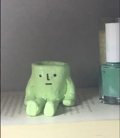 a green toy sitting on top of a book next to a bottle