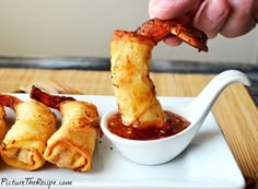 a person dipping some food into a small bowl