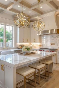 a kitchen with marble counter tops and gold accents on the ceiling, along with two stools