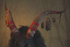 an animal with long horns and red scarfs on it's head is standing in front of a wall