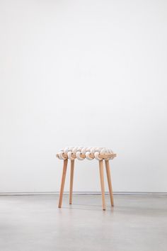 three wooden stools sitting on top of a cement floor next to a white wall