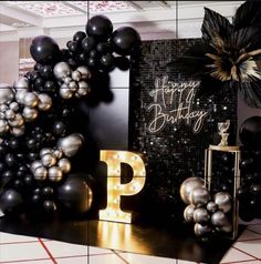 black and gold balloons are on display in front of a happy birthday sign with the letter p