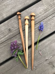 three wooden candlesticks sitting on top of a wooden table next to purple flowers