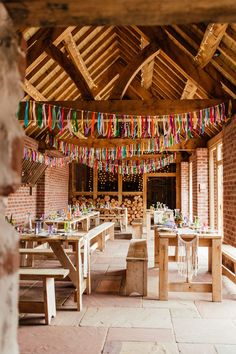 the inside of a building with tables and benches covered in colorful streamers hanging from the ceiling