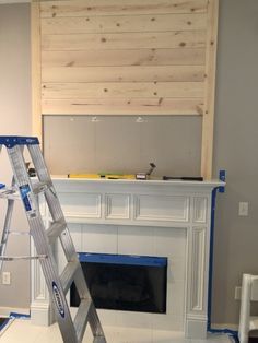 a man standing on a ladder in front of a fireplace with a wooden panel over it