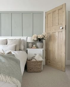 a white bed sitting next to a wooden door in a bedroom on top of a carpeted floor