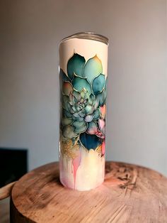 a colorful vase sitting on top of a wooden table next to a plant in it