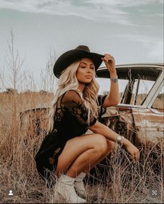 Girl in field, blonde western vibe with black felt cowboy hat and western silver jewelry in black western lace dress and tan cowgirl boots, posed crouched down Country 30th Birthday Photoshoot, Western Female Photoshoot, Fall Photoshoot Western, Cowboy Hat Pictures Photo Shoot, Cowgirl Inspired Photoshoot, Vintage 50s Photoshoot, Western Whiskey Photoshoot, Southern Photoshoot Ideas, Western Outdoor Photoshoot