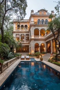 an outdoor swimming pool in front of a large house