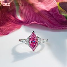 a pink diamond ring sitting on top of a flower