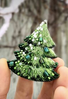 someone is holding a green christmas tree brooch