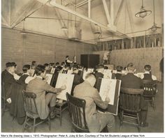 an old black and white photo of people sitting at desks in front of paintings