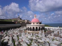 an old cemetery with many headstones and a pink dome on the top, overlooking the ocean