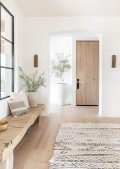 a wooden bench sitting in the middle of a living room next to a white wall