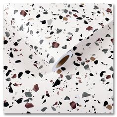 a white wallpaper with black and brown spots on it's surface, next to a roll of tissue paper