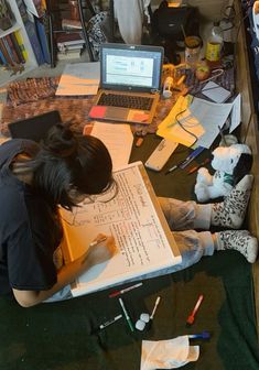 a woman is sitting on the floor with her laptop and papers in front of her