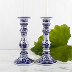 two blue and white candlesticks sitting next to each other on a marble surface