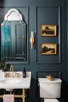 a white toilet sitting next to a bathroom sink under a mirror on top of a wall