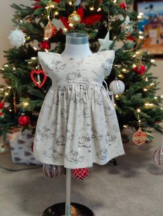 a dress on a mannequin in front of a christmas tree with ornaments around it