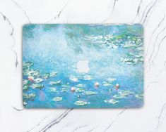 a macbook cover with an image of water lilies on the surface in blue and green