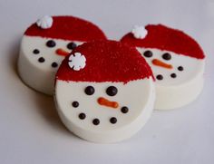 three decorated snowman cookies sitting on top of a table