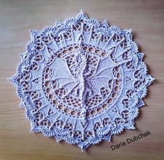 a white doily on a wooden table with the words daria dubchak written below it