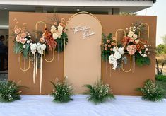 an outdoor event with flowers and greenery on the wall