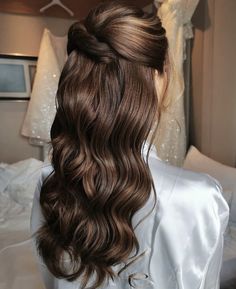 the back of a woman's head with long hair in a half updo