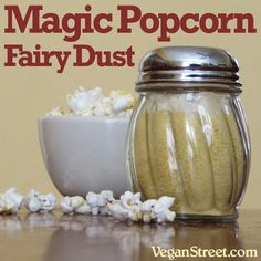 a jar filled with popcorn sitting on top of a table next to a bowl of popcorn