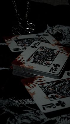 three playing cards with blood on them sitting on a table