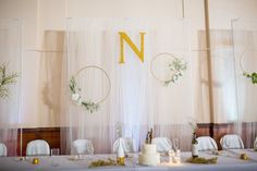 the table is set up with white linens and greenery, along with two cakes