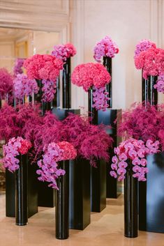 several black vases with pink flowers in them