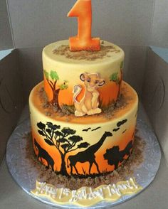 a two tiered cake with an animal theme on the top and number one on the bottom