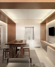 a modern kitchen with white cabinets and wood accents is seen in this image from the dining room