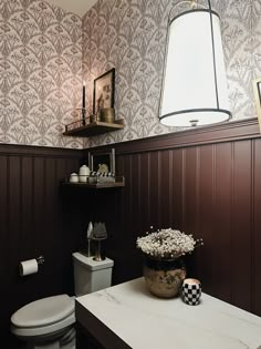 a white toilet sitting in a bathroom next to a wooden shelf with flowers on it