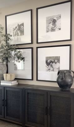 a living room with pictures on the wall and a vase sitting on top of it