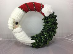 a crocheted christmas wreath with santa clause on it and a candy cane in the middle