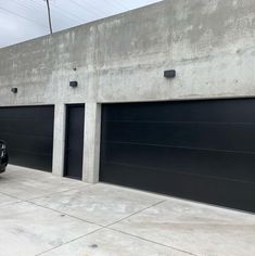 a black car parked in front of two garage doors