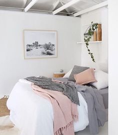 a bed with blankets and pillows in a bedroom next to a wall hanging on the wall