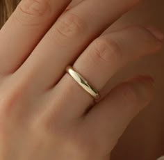 a woman's hand with a gold ring on her finger, close up view