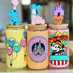 three glass jars with mickey mouse magnets on top of each one in different colors