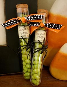 two bottles filled with green grapes sitting on top of a table next to an orange vase