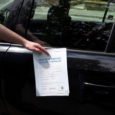 a person holding up a parking ticket in front of a car