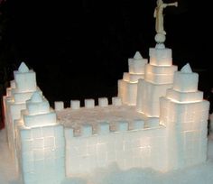 an ice castle with a statue on top and snow around the edges, in front of a black background