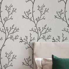 a white couch sitting next to a wall with black branches on it