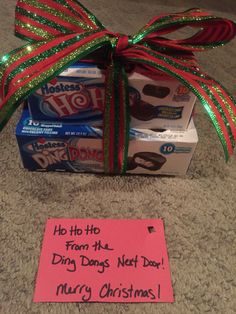 a candy box wrapped in red and green ribbon next to a pink note that says ho ho ho from the dirty dogs not day merry christmas